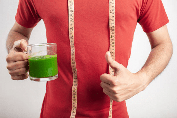 A man holding athletic greens to drink