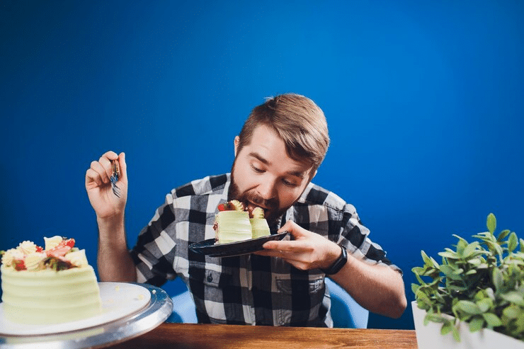 A man who is craving to eat more cake during intermittent fasting cheat day